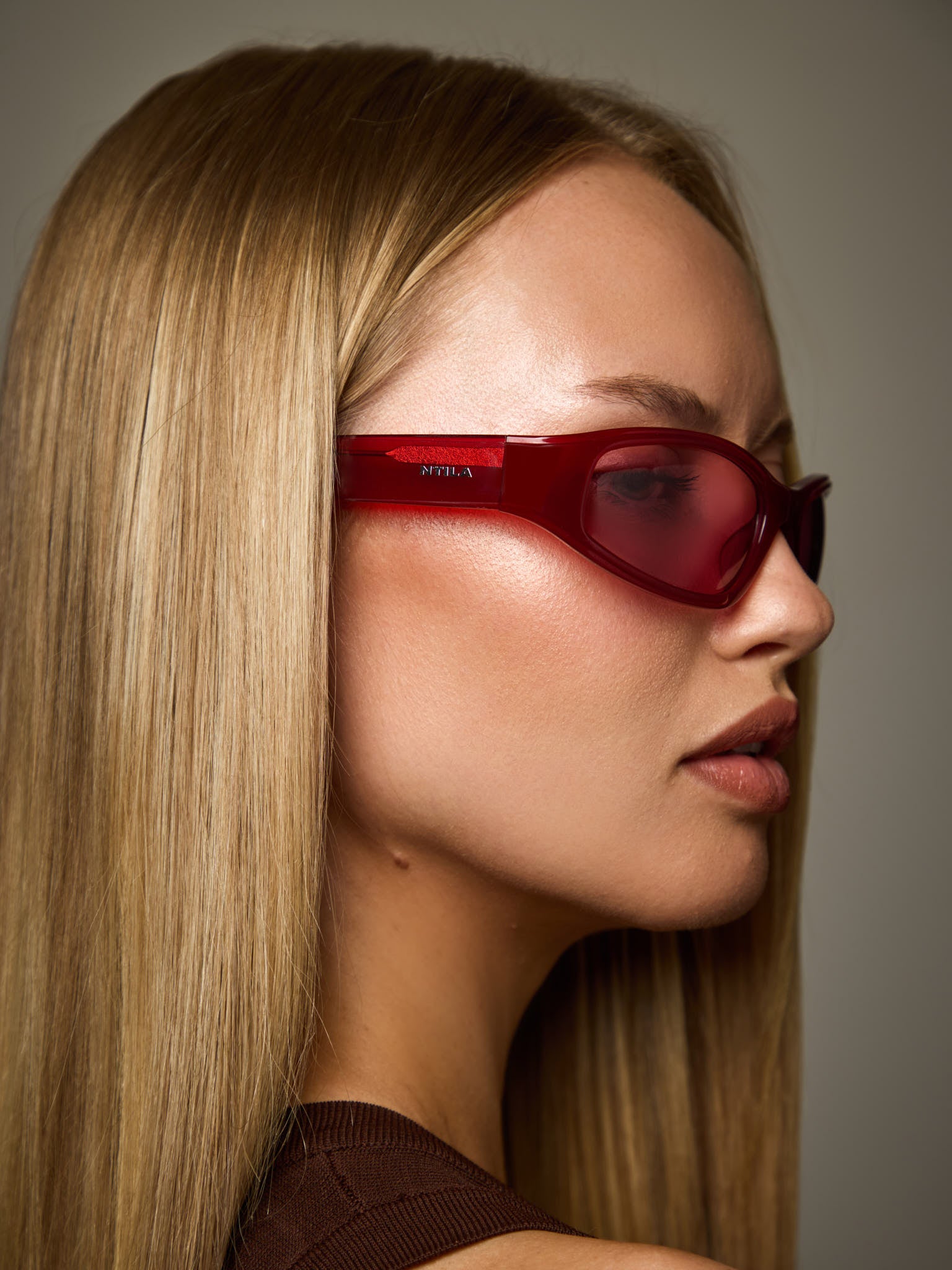 Woman wearing ace red oval sunglasses with a neutral background