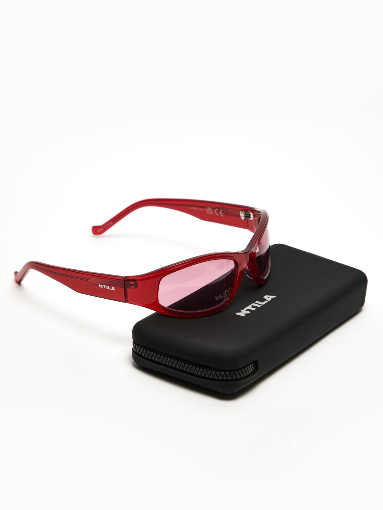 Ace red oval sunglasses with pink lenses on a black case against a white background
