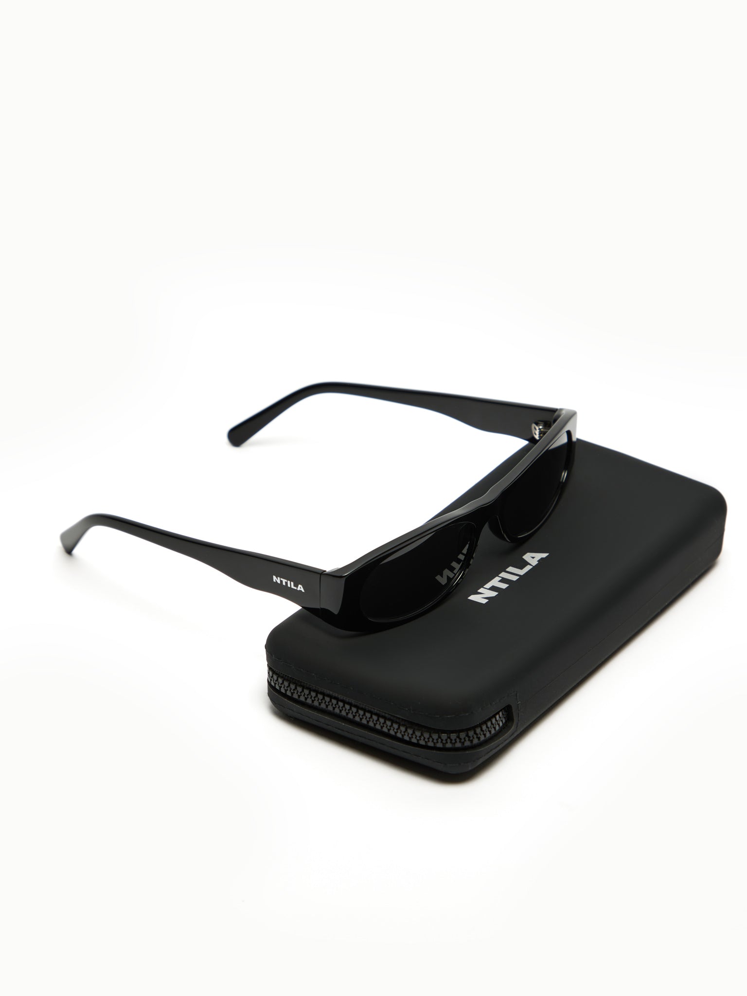 NTILA black Leni sunglasses on a black case with 'NTILA' branding on a white background