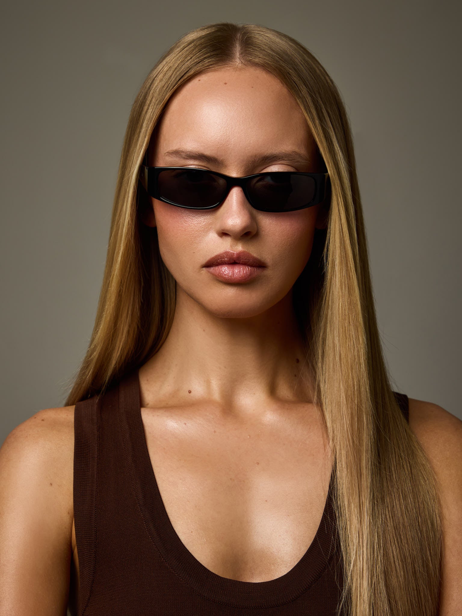 Woman wearing NTILA Roko Black sunglasses and a black top against a grey background