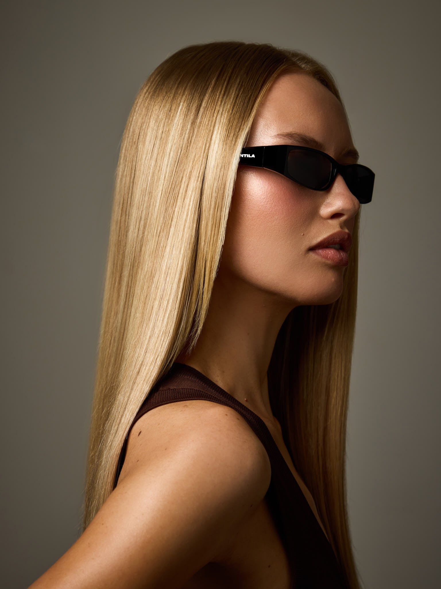 Woman wearing NTILA Roko black sunglasses against a grey background