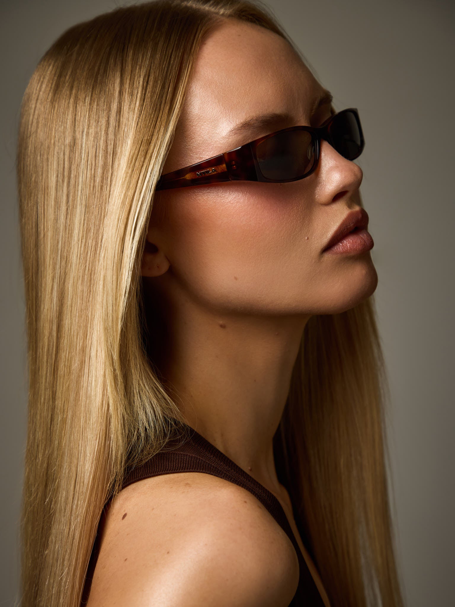 Woman wearing NTILA black tort tortoise shell Roko sunglasses with a neutral background