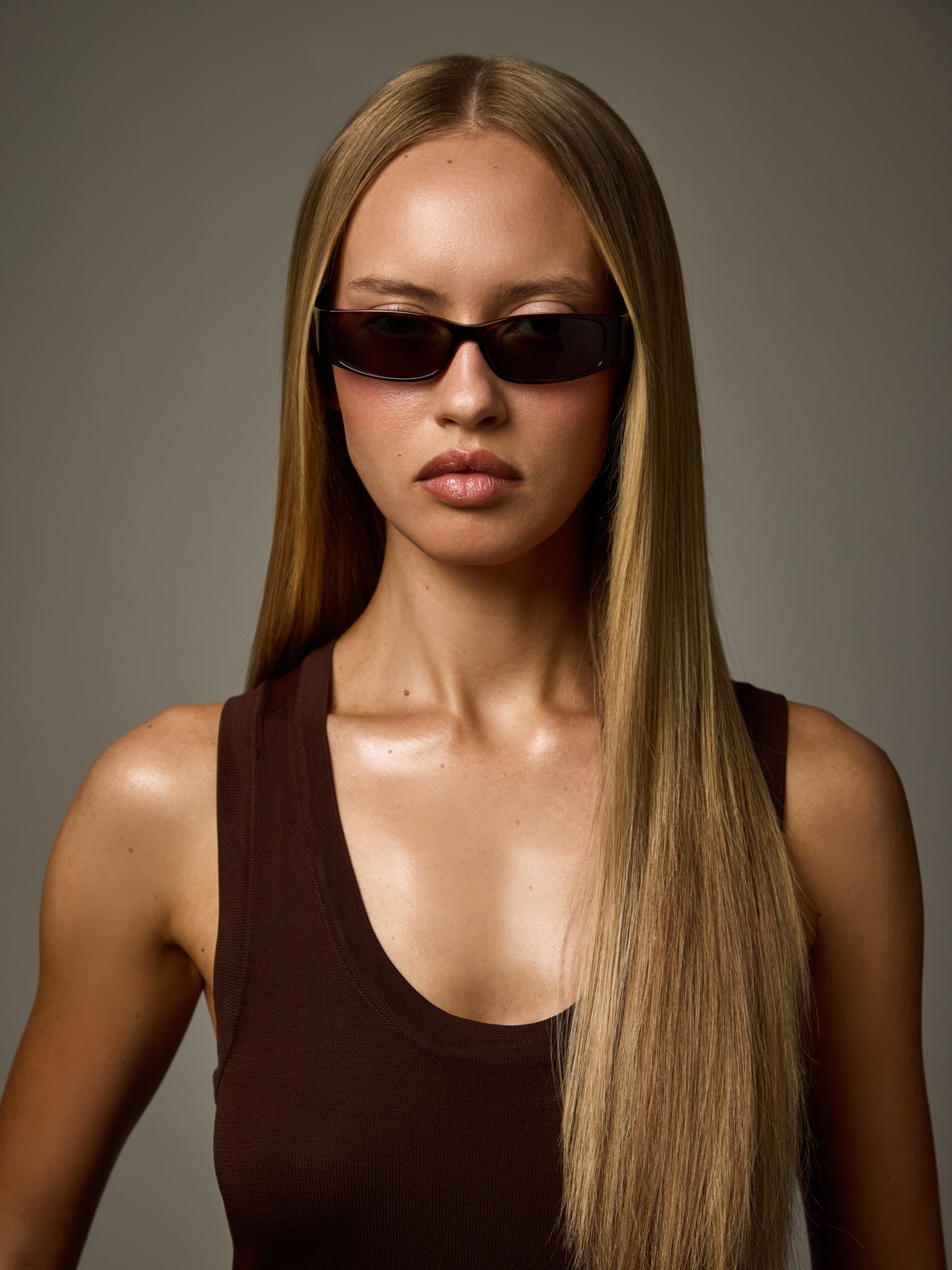 Woman wearing NTILA Roko black tort tortoise shell sunglasses against a grey background