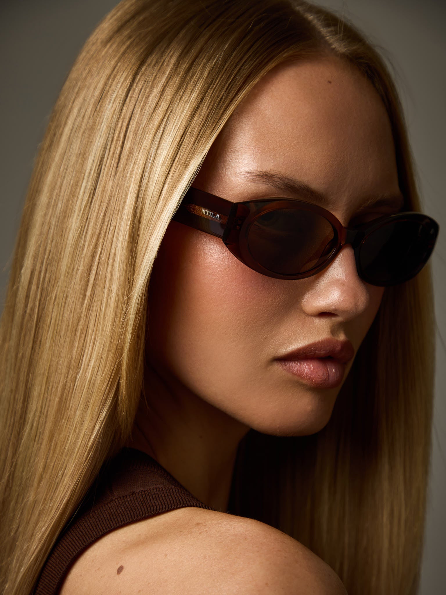 Close-up of a woman wearing Cleo brown oval sunglasses with a neutral background