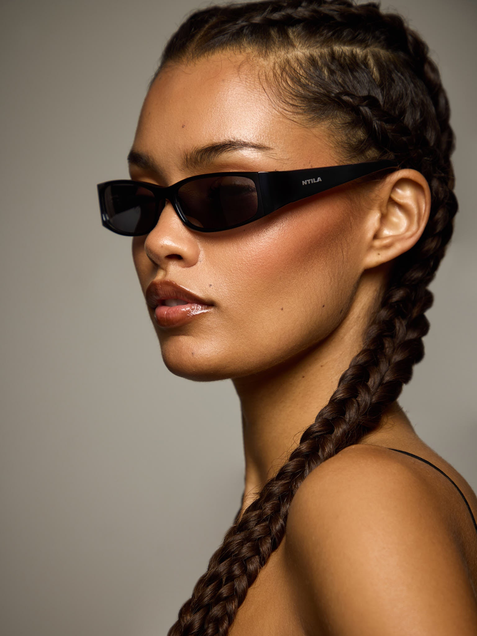 Woman wearing NTILA Roko black sunglasses with a neutral background